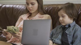 Allvarlig äldre syster och mer ung liten broder som sitter på lädersoffan r arkivfilmer Allvarlig äldre syster och mer ung liten broder som sitter på lädersoffan r arkivfilmer