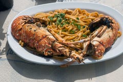 Almoço delicioso pelo mar Uma placa branca dos espaguetes com as lagostas enormes na grade foto de stock Almoço delicioso pelo mar Uma placa branca dos espaguetes com as lagostas enormes na grade foto de stock
