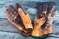 Alte Handschuhe der schmutzigen Arbeit auf einem Holztisch befleckt mit Fett und ?l Darstellung von Berufen des hohen Risikos und lizenzfreie stockbilder Alte Handschuhe der schmutzigen Arbeit auf einem Holztisch befleckt mit Fett und ?l Darstellung von Berufen des hohen Risikos und lizenzfreie stockbilder