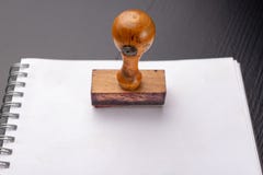 Alter hölzerner Stempel auf einem weißen Stück des Notizbuches Bürozusätze auf einer Tabelle stockbilder Alter hölzerner Stempel auf einem weißen Stück des Notizbuches Bürozusätze auf einer Tabelle stockbilder