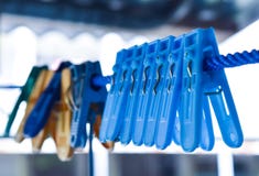 Plastic cloth clips hang on the blue rope for clamp clothes after washing. Stock Images Plastic cloth clips hang on the blue rope for clamp clothes after washing. Stock Images