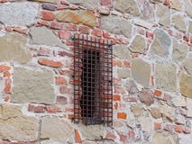 Alvenaria de pedra medieval antiga com uma janela forjada fechado da estrutura Textura de um fragmento de uma parede de uma estru foto de stock Alvenaria de pedra medieval antiga com uma janela forjada fechado da estrutura Textura de um fragmento de uma parede de uma estru foto de stock
