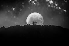Amazing love scene. Silhouettes of young romantic couple standing under the moon light stock image Amazing love scene. Silhouettes of young romantic couple standing under the moon light stock image