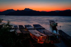 Amazing sunset in luang prabang over the mekong river. Tourist and house boats in the water. Sky is on fire. stock photography Amazing sunset in luang prabang over the mekong river. Tourist and house boats in the water. Sky is on fire. stock photography