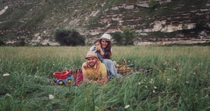 Amazing young family with the baby at the picnic in the middle of nature looking through to the camera and smiling stock footage Amazing young family with the baby at the picnic in the middle of nature looking through to the camera and smiling stock footage