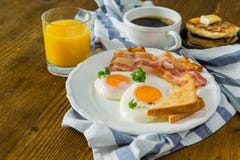 American breakfast with sunny side up eggs, bacon, toast, pancakes, coffee and juice Stock Photos American breakfast with sunny side up eggs, bacon, toast, pancakes, coffee and juice Stock Photos