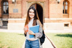 Amerikanischer Hochschulstudent, der auf dem Campus mit Kaffee- und Buchtasche lächelt lizenzfreie stockfotos Amerikanischer Hochschulstudent, der auf dem Campus mit Kaffee- und Buchtasche lächelt lizenzfreie stockfotos