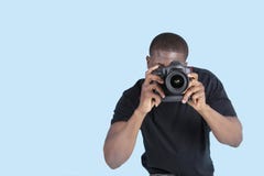 Amerykanina Afrykańskiego Pochodzenia młody człowiek bierze fotografię przez cyfrowej kamery nad błękitnym tłem zdjęcie royalty free Amerykanina Afrykańskiego Pochodzenia młody człowiek bierze fotografię przez cyfrowej kamery nad błękitnym tłem zdjęcie royalty free