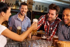 Amici che bevono birra al contatore in pub immagine stock libera da diritti Amici che bevono birra al contatore in pub immagine stock libera da diritti