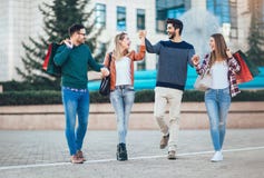Amici che camminano lungo la via con i sacchetti della spesa Fotografia Stock Amici che camminano lungo la via con i sacchetti della spesa Fotografia Stock