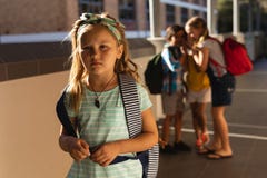 Amici della scuola che opprimono una ragazza triste nel corridoio di scuola elementare fotografia stock libera da diritti Amici della scuola che opprimono una ragazza triste nel corridoio di scuola elementare fotografia stock libera da diritti