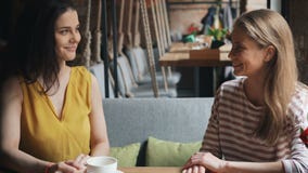 Amigos de jovens senhoras alegres que falam rindo da tabela no café que aprecia o lazer filme Amigos de jovens senhoras alegres que falam rindo da tabela no café que aprecia o lazer filme