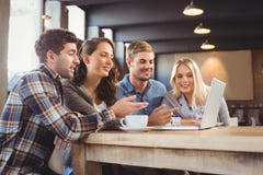 Amigos de sorriso que bebem o café e que apontam na tela do portátil foto de stock Amigos de sorriso que bebem o café e que apontam na tela do portátil foto de stock