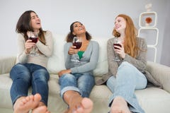 Amigos femeninos jovenes alegres con las copas de vino en casa fotos de archivo libres de regalías Amigos femeninos jovenes alegres con las copas de vino en casa fotos de archivo libres de regalías