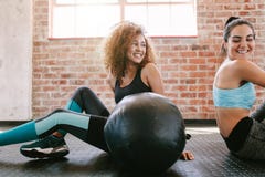 Amigos femeninos que toman una rotura del entrenamiento en gimnasio fotografía de archivo libre de regalías Amigos femeninos que toman una rotura del entrenamiento en gimnasio fotografía de archivo libre de regalías