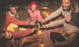 Amigos novos do moderno que têm o divertimento junto no partido da praia da noite fotografia de stock Amigos novos do moderno que têm o divertimento junto no partido da praia da noite fotografia de stock