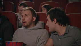 Amigos wathcing película en cine Hombre que previene a los amigos que miran la película Amigos wathcing película en cine Hombre que previene a los amigos que miran la película
