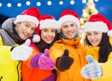 Amis heureux dans des chapeaux de Santa et des costumes de ski dehors images libres de droits Amis heureux dans des chapeaux de Santa et des costumes de ski dehors images libres de droits
