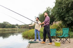 Amis masculins avec les cannes à pêche sur le pilier de lac photos libres de droits Amis masculins avec les cannes à pêche sur le pilier de lac photos libres de droits