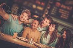 Amis multiraciaux gais ayant l'amusement mangeant dans la pizzeria photo libre de droits Amis multiraciaux gais ayant l'amusement mangeant dans la pizzeria photo libre de droits