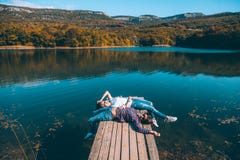 Amis s'asseyant sur le pair par le lac image stock Amis s'asseyant sur le pair par le lac image stock