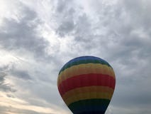 Ampuła barwiąca jaskrawa round tęcza barwił pasiastego pasiastego latanie balon z koszem przeciw niebu w wieczór zdjęcia royalty free Ampuła barwiąca jaskrawa round tęcza barwił pasiastego pasiastego latanie balon z koszem przeciw niebu w wieczór zdjęcia royalty free