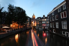 Amsterdam kanaler och härliga byggnader nära floden på, lång exponering för afton royaltyfria foton Amsterdam kanaler och härliga byggnader nära floden på, lång exponering för afton royaltyfria foton