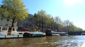 Amsterdam, Netherlands. 25.04.2019. Old ships parked in the canals of Amsterdam. View from the tour boat. Shot with a stock footage Amsterdam, Netherlands. 25.04.2019. Old ships parked in the canals of Amsterdam. View from the tour boat. Shot with a stock footage