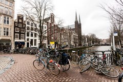 Amsterdão, os Países Baixos - 26 de fevereiro de 2010: Bicicletas na rua perto do canal da água A bicicleta é transporte muito po imagem de stock royalty free Amsterdão, os Países Baixos - 26 de fevereiro de 2010: Bicicletas na rua perto do canal da água A bicicleta é transporte muito po imagem de stock royalty free