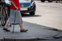 An Old Woman With A Stick Goes Across The Street. Royalty Free Stock Photos