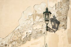 An ancient dark green squiggly lantern casting a cloud over a grungy house wall in Prag royalty free stock photography An ancient dark green squiggly lantern casting a cloud over a grungy house wall in Prag royalty free stock photography