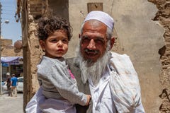 An elderly Iranian man of the Baluchi ethnic group shows happiness by holding his granddaughter in his arms.
