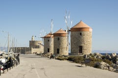 Ancient windmills on stony Rhodes coastline in harbor, old historic buildings, place of interest, blue sky stock photos Ancient windmills on stony Rhodes coastline in harbor, old historic buildings, place of interest, blue sky stock photos