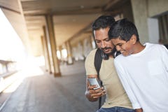 Angenehmer hindischer Vater, der sein Telefon mit seinem Sohn verwendet lizenzfreie stockbilder Angenehmer hindischer Vater, der sein Telefon mit seinem Sohn verwendet lizenzfreie stockbilder