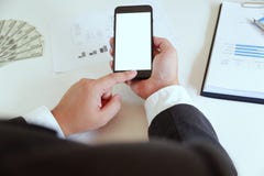 Angolo alto dell'uomo facendo uso dello smartphone in ufficio con soldi sullo scrittorio funzionante fotografie stock Angolo alto dell'uomo facendo uso dello smartphone in ufficio con soldi sullo scrittorio funzionante fotografie stock