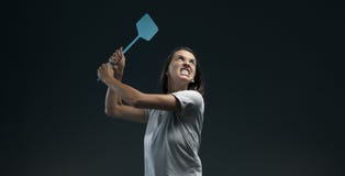 Angry woman killing mosquitoes with a fly swatter