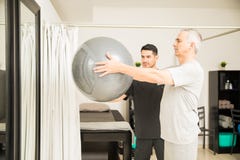 Anhebender Übungs-Ball Physiotherapeuten-Assisting Elderly Mans stockfotos Anhebender Übungs-Ball Physiotherapeuten-Assisting Elderly Mans stockfotos