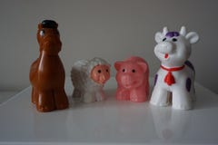 Animais plásticos da exploração agrícola na prateleira branca imagem de stock Animais plásticos da exploração agrícola na prateleira branca imagem de stock