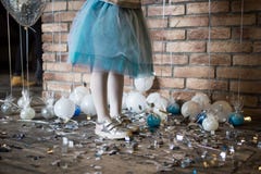 Aniversário da criança Um bebê nas sapatilhas prateadas e em uma saia suntuoso do tule No assoalho são os balões pequenos imagens de stock royalty free Aniversário da criança Um bebê nas sapatilhas prateadas e em uma saia suntuoso do tule No assoalho são os balões pequenos imagens de stock royalty free