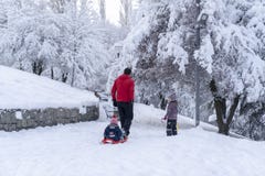 Ankara/die Türkei - 26. Dezember 2018: Die hintere Ansicht des Vaters sein kleines Baby rodelnd und eine andere Tochter gehen mit lizenzfreie stockfotografie Ankara/die Türkei - 26. Dezember 2018: Die hintere Ansicht des Vaters sein kleines Baby rodelnd und eine andere Tochter gehen mit lizenzfreie stockfotografie