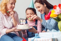 Anniversaire de mère et de fille de grand-mère ensemble à la maison se reposant jugeant le gâteau gai image stock Anniversaire de mère et de fille de grand-mère ensemble à la maison se reposant jugeant le gâteau gai image stock