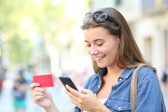 Années de l'adolescence heureuses achetant en ligne avec un smartphone dans la rue images stock Années de l'adolescence heureuses achetant en ligne avec un smartphone dans la rue images stock