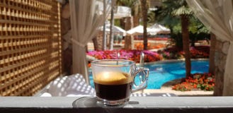 Anseende för svart kaffe på hotellfönster med sikt på utvändig pöl arkivfoton Anseende för svart kaffe på hotellfönster med sikt på utvändig pöl arkivfoton