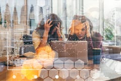 Ansicht durch Glas Zwei Geschäftsfrauen sitzen vor dem Laptop und erfassen ihre Köpfe Brainstorming, Teamwork lizenzfreie stockfotografie Ansicht durch Glas Zwei Geschäftsfrauen sitzen vor dem Laptop und erfassen ihre Köpfe Brainstorming, Teamwork lizenzfreie stockfotografie