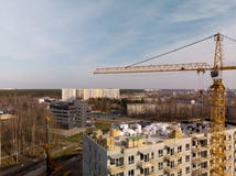 Antenne d'un chantier avec une grande grue jaune lumineuse fonctionnante près d'une maison images libres de droits Antenne d'un chantier avec une grande grue jaune lumineuse fonctionnante près d'une maison images libres de droits