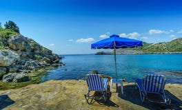 Anthony Quinn Bay secluded beach with umbrella and chairs stock photo Anthony Quinn Bay secluded beach with umbrella and chairs stock photo