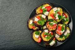 Aperitivos - berenjenas asadas a la parrilla con ajo, queso feta y tomates imagenes de archivo Aperitivos - berenjenas asadas a la parrilla con ajo, queso feta y tomates imagenes de archivo
