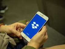 App móvel de abertura do Dropbox da mulher com logotipo na tela do iPhone ao comutar no metro imagem de stock App móvel de abertura do Dropbox da mulher com logotipo na tela do iPhone ao comutar no metro imagem de stock