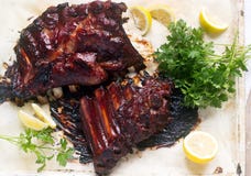 Appetizing baked glazed veal or pork ribs served with lemon and herbs. stock photography Appetizing baked glazed veal or pork ribs served with lemon and herbs. stock photography