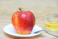 Apple on a white plate with a spoon peppered with honey on wooden background royalty free stock photography Apple on a white plate with a spoon peppered with honey on wooden background royalty free stock photography
